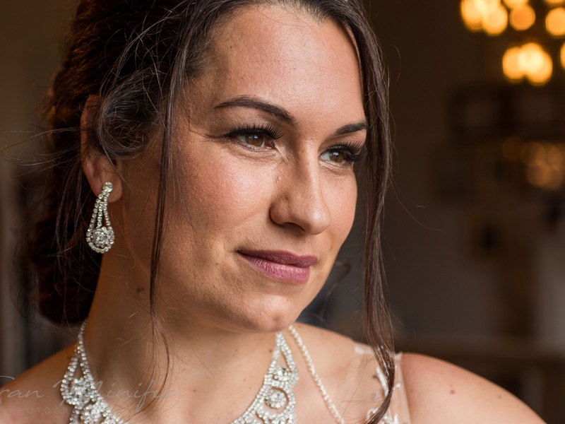Professional bridal shoot - blonde bride full length with white and green bouquet, ruffled gown by vine wall